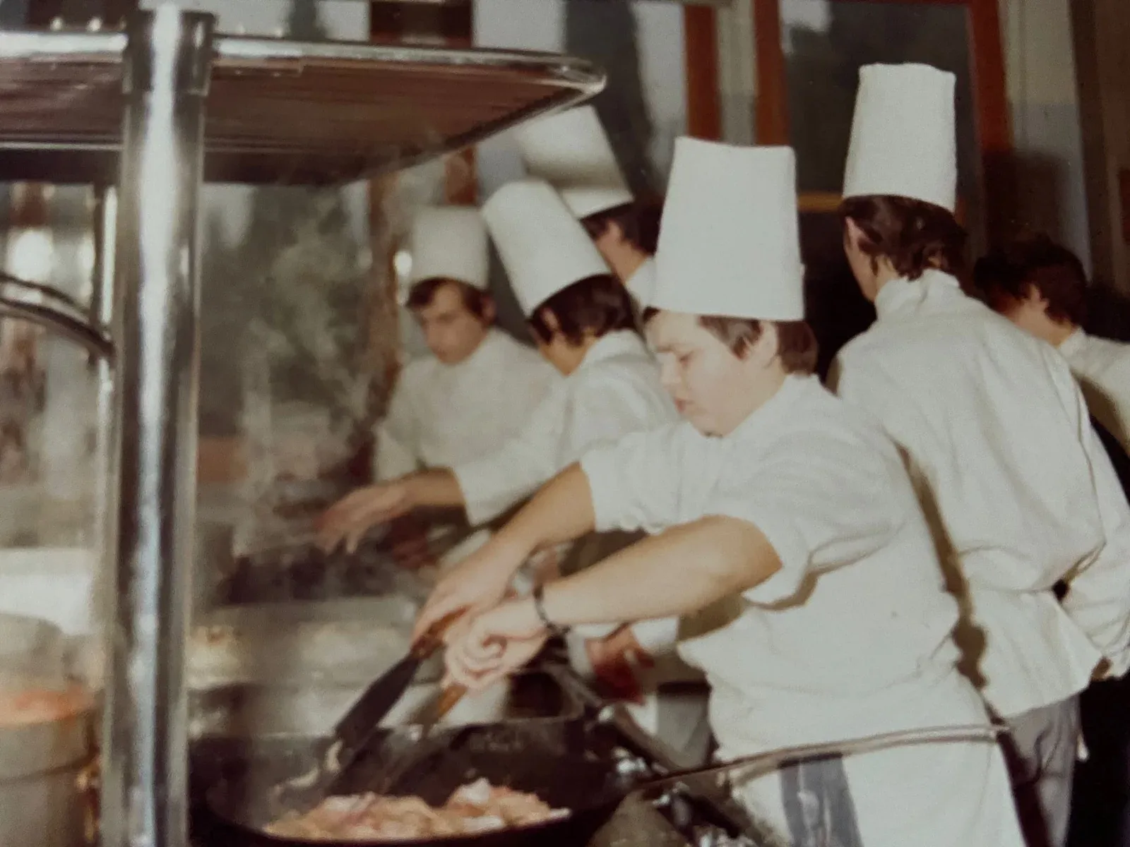 Young cooks in white toques working together at a restaurant range