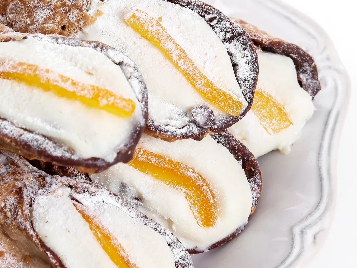 Close-up of cannoli with dark-rimmed shells and orange garnish plated at Davanti