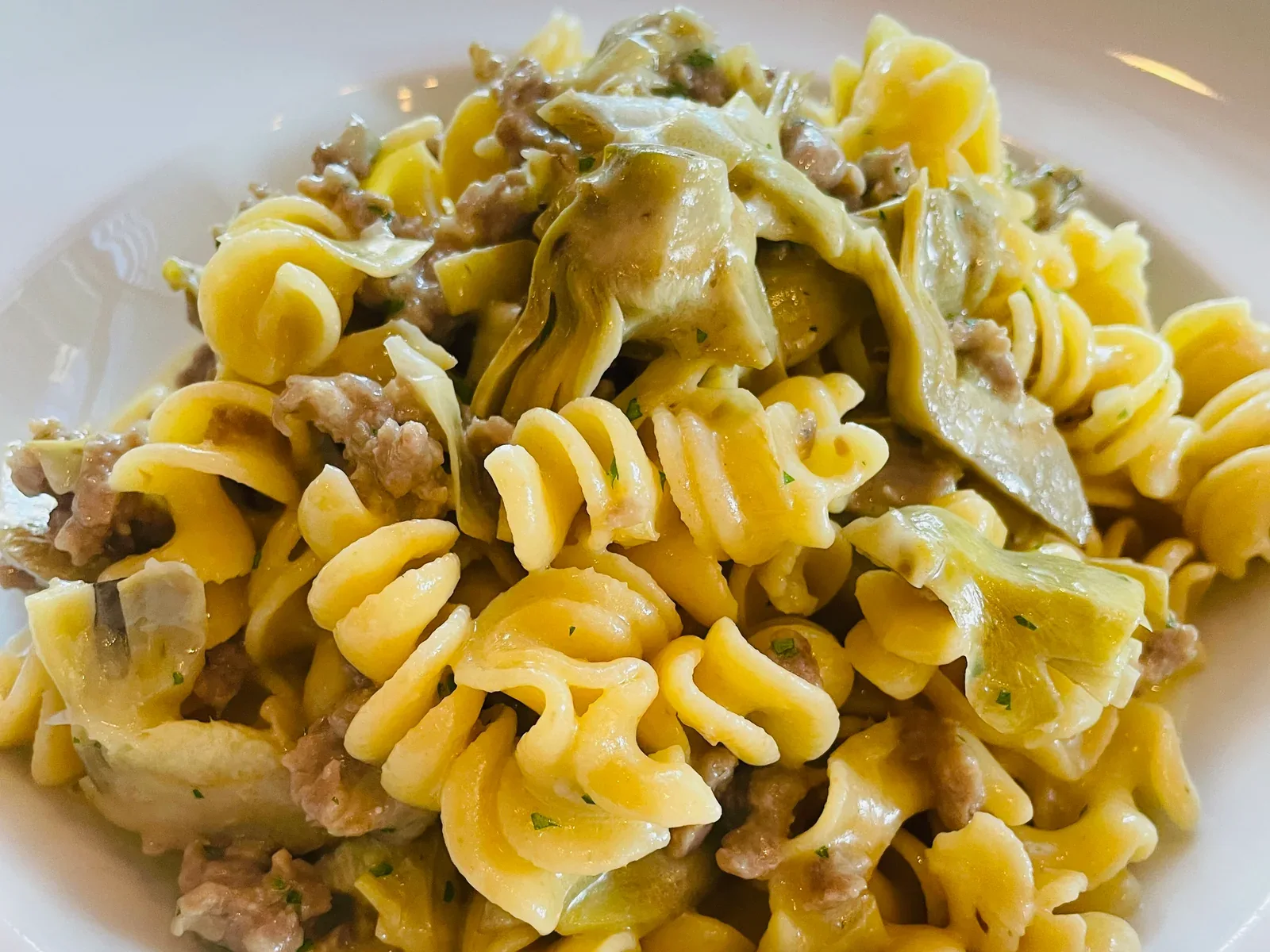 Close view of fresh fusilli with artichokes and sausage plated at Davanti
