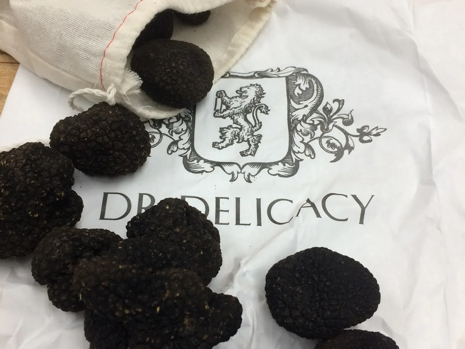 Dark truffles gathered on a printed cloth beside a drawstring bag