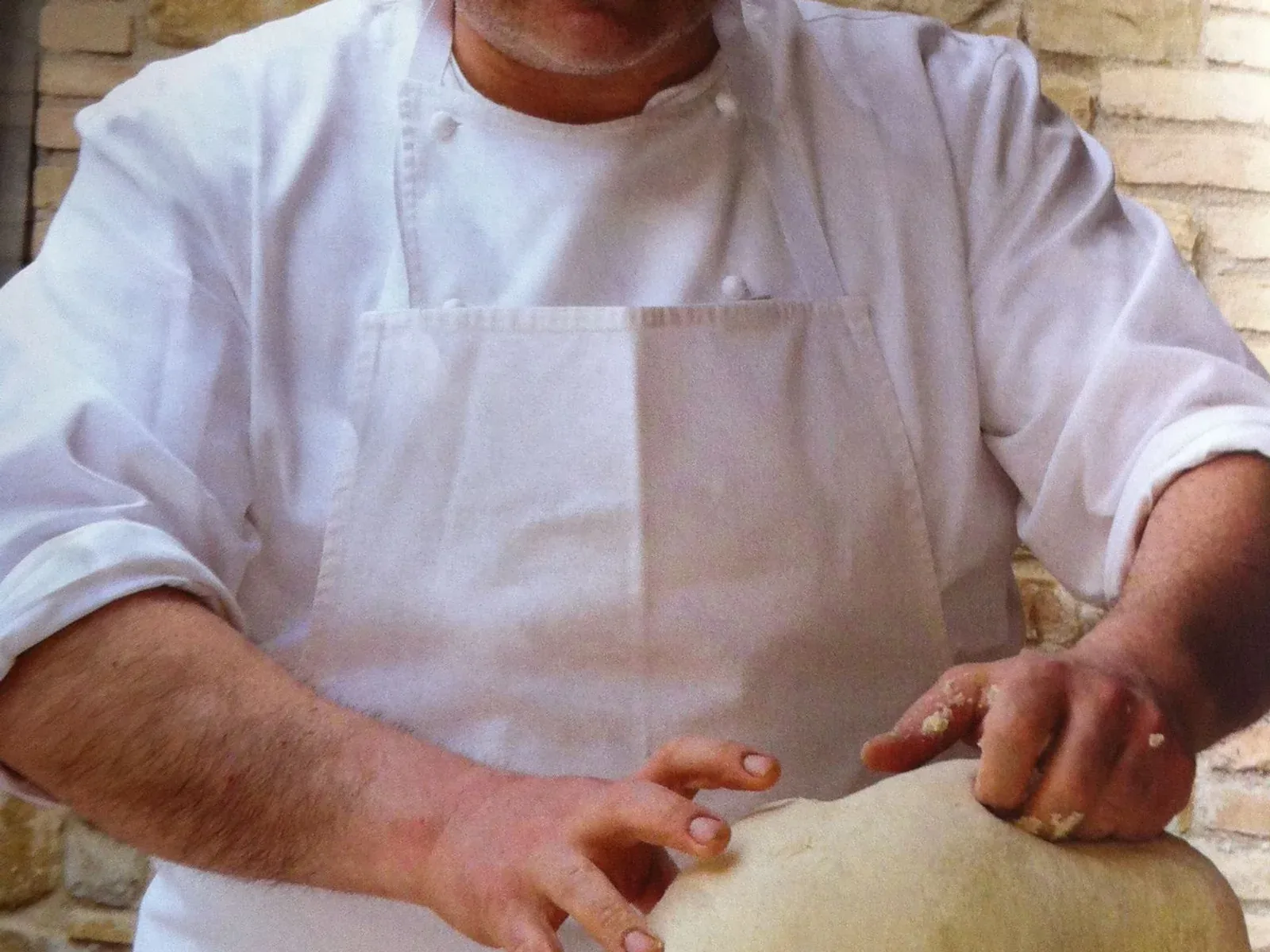 Chef Roberto Crescini’s flour-dusted hands shaping a large mound of fresh dough