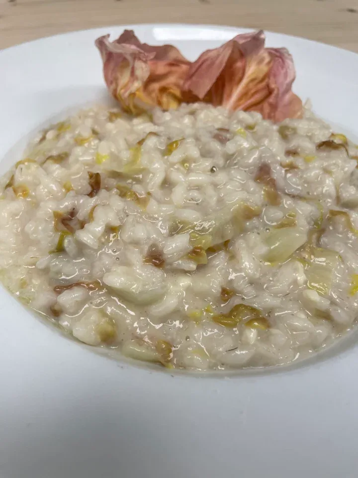 Creamy risotto with pieces of radicchio and pink radicchio leaves on a white plate