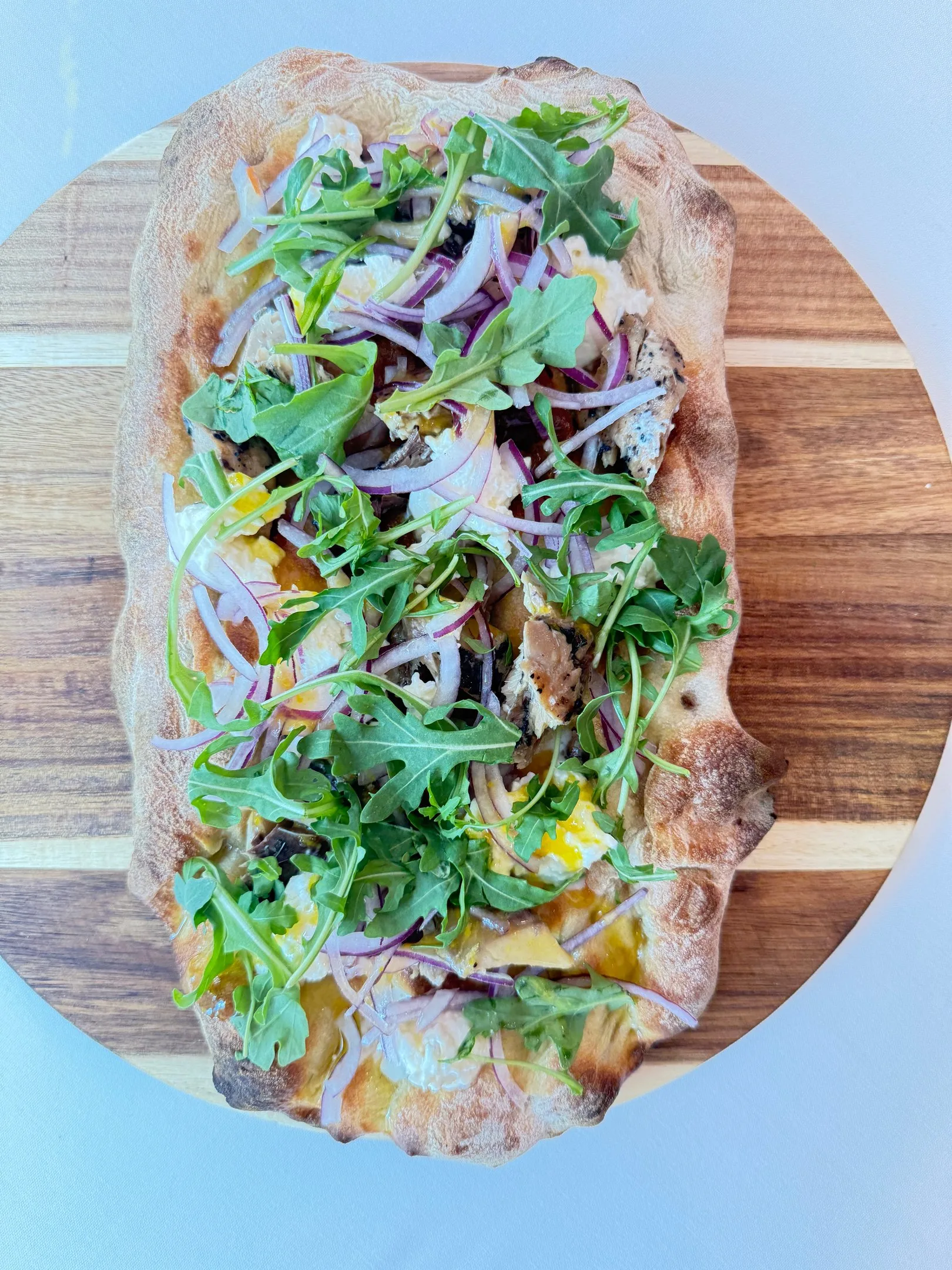 An oval pinsa with arugula and red onion at Davanti