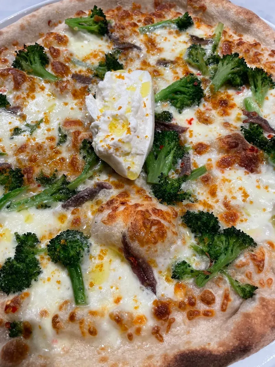 Davanti pizza with green broccoletti, anchovies and burrata on a browned crust