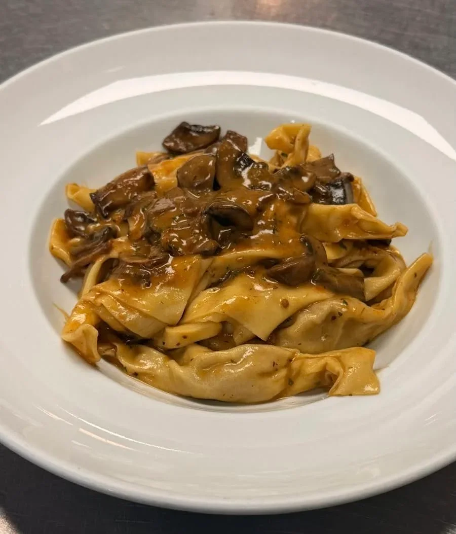 Meat-filled ravioli covered with creamy brown mushroom sauce and sliced mushrooms on a white plate