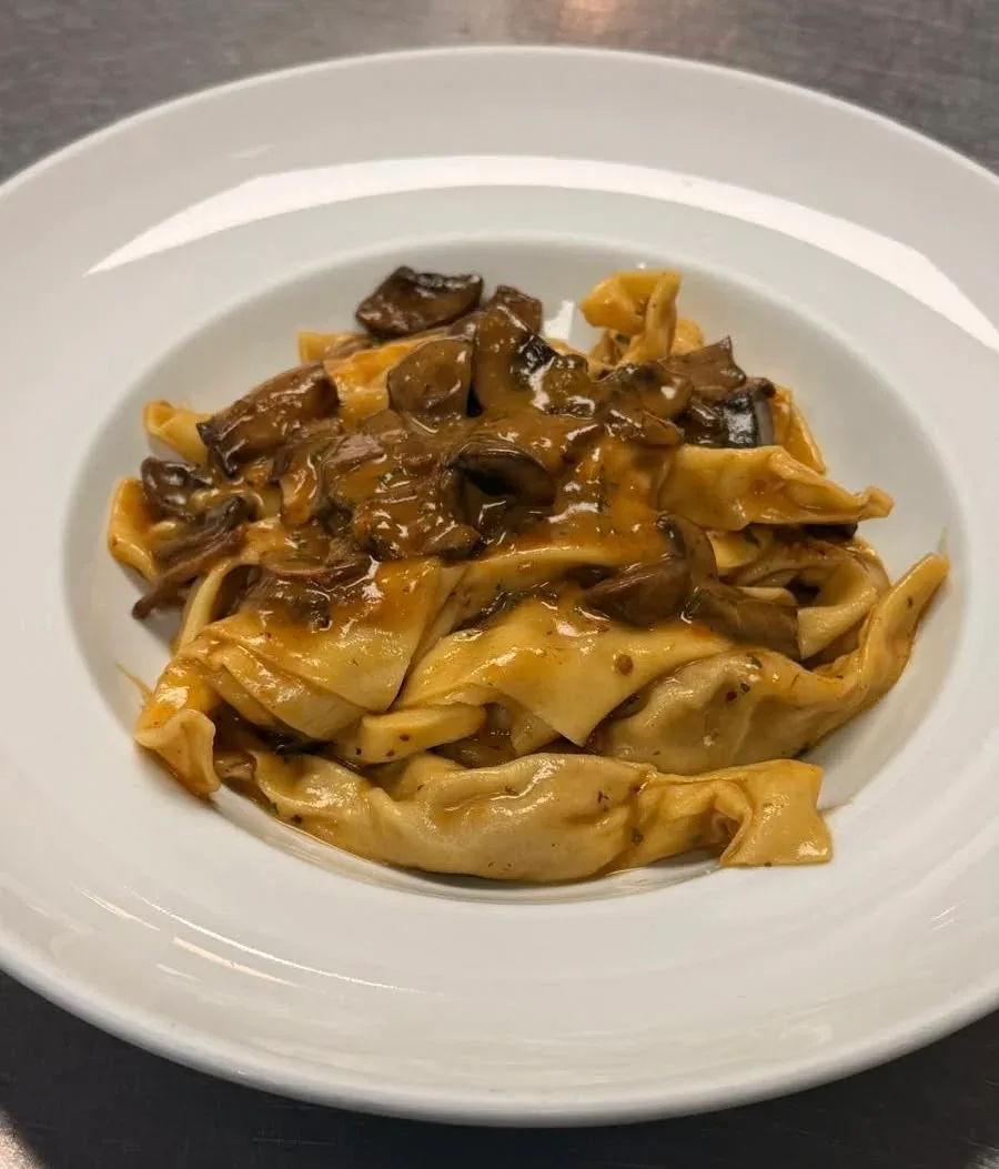 Meat-filled ravioli covered with creamy brown mushroom sauce and sliced mushrooms on a white plate