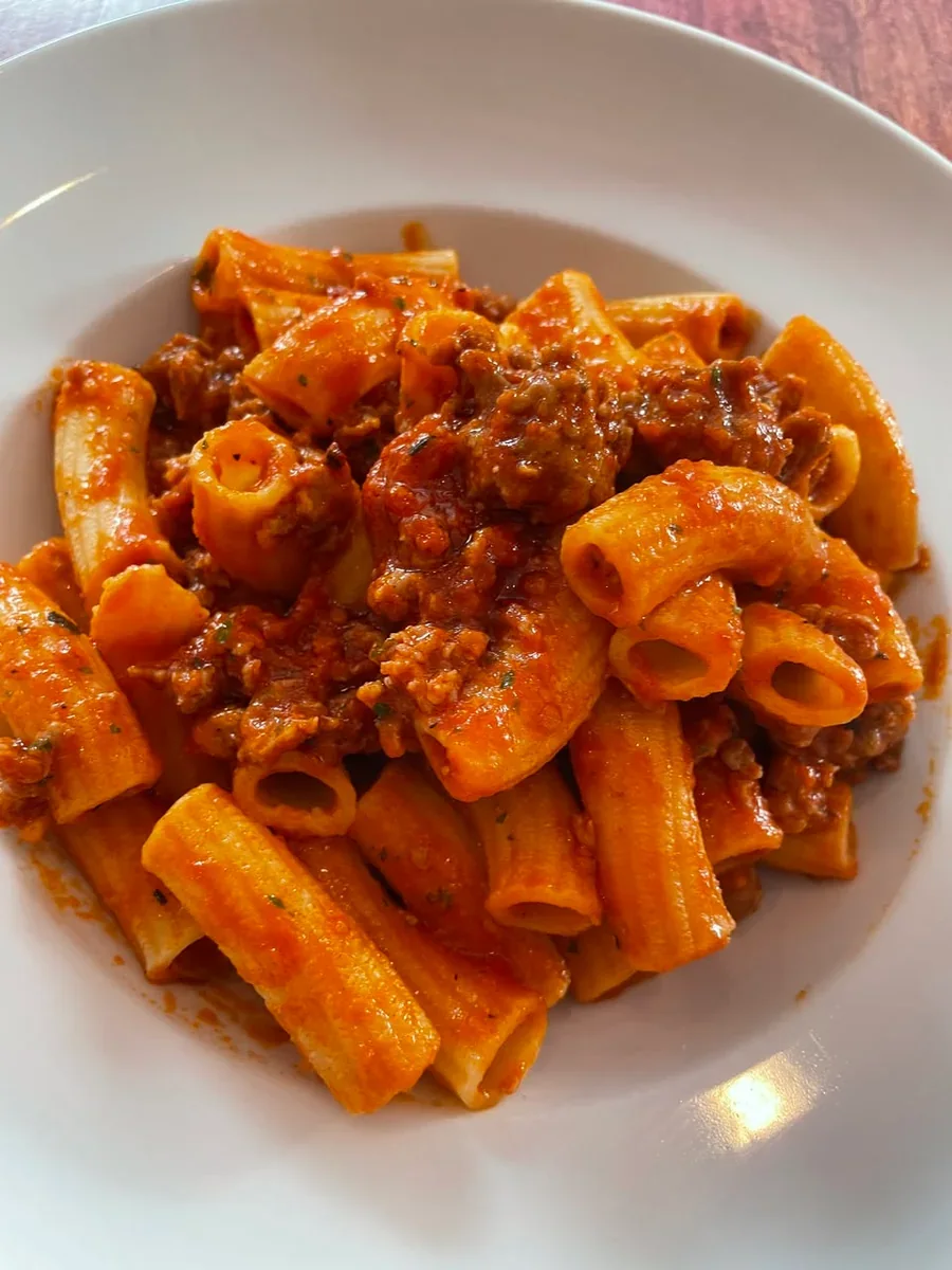 Small rigatoni coated in tomato sauce with pieces of sausage at Davanti